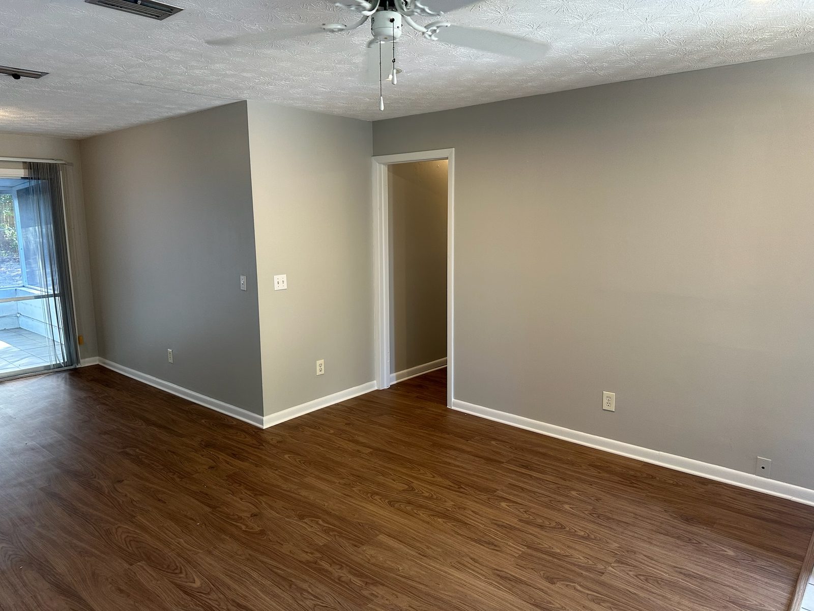 Freshly painted living room with light gray walls, white trim, and wood-look floors